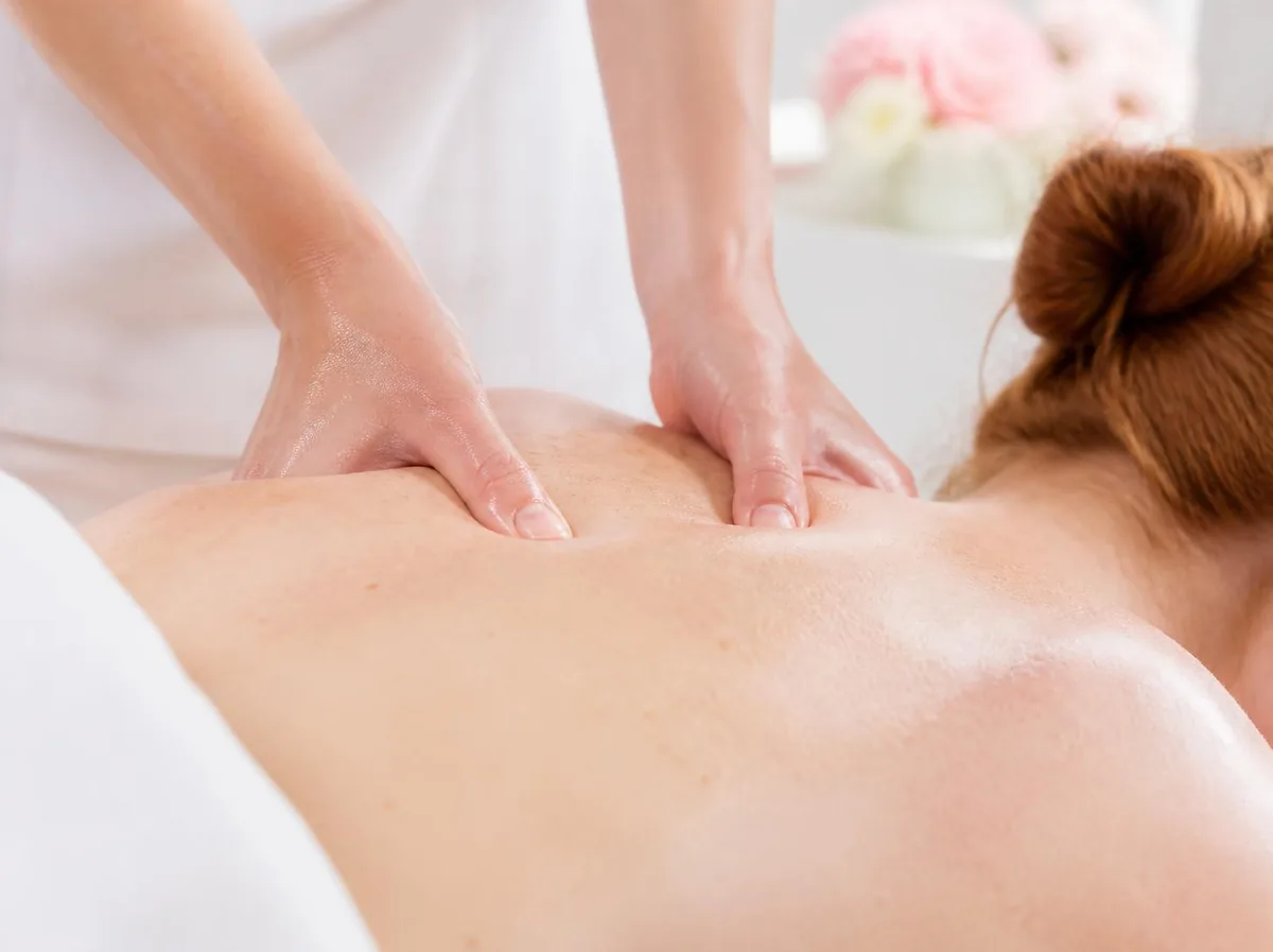 Close-up of a therapist’s thumbs working along a guest’s shoulder blade