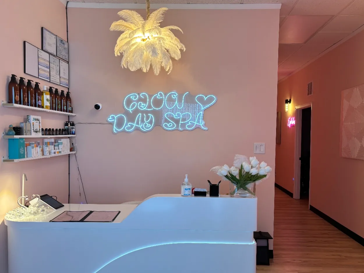 Glow Day Spa reception with blush walls, a white front desk and the neon Glow sign